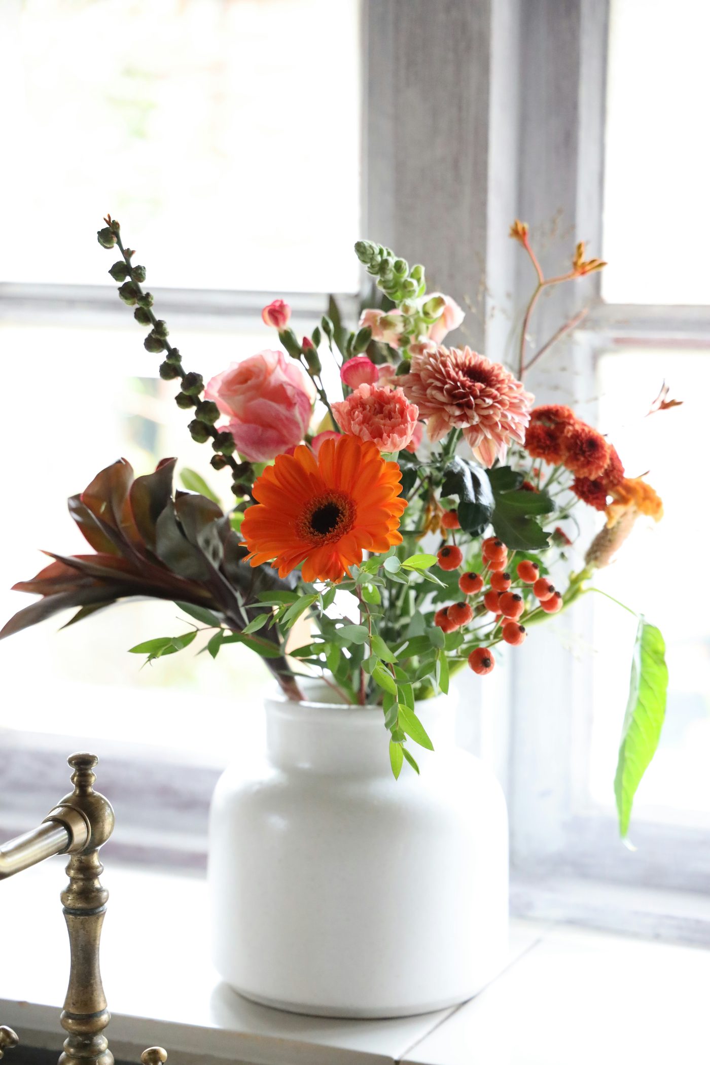 Bunte Blumen in einer Vase am Fenster